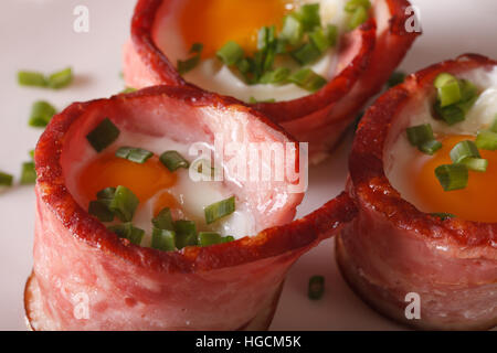 Colazione: uova fritte avvolto in pancetta su una piastra macro. orizzontale Foto Stock