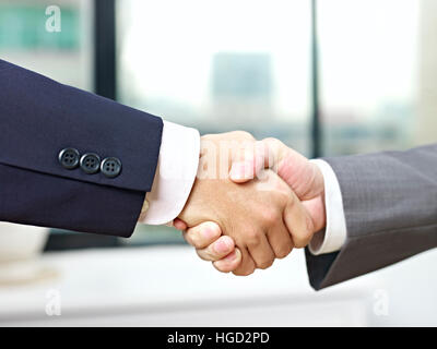 Close-up di una stretta di mano ferma in ufficio da parte di due imprenditori asiatici. Foto Stock