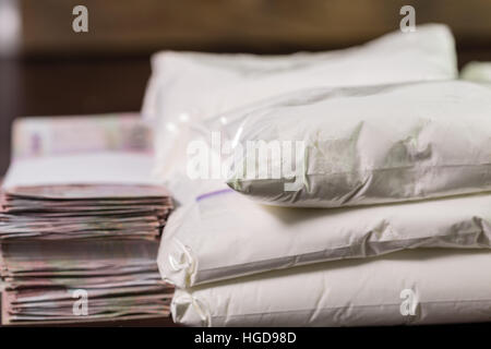 Stash di eroina farmaci sulla tavola in buste trasparenti con i soldi in pile Foto Stock