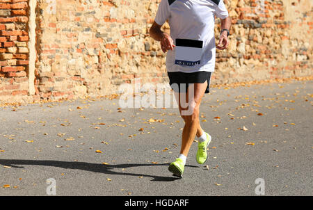 Senior runner corre con abbigliamento sportivo e il muro di mattoni rossi su sfondo Foto Stock