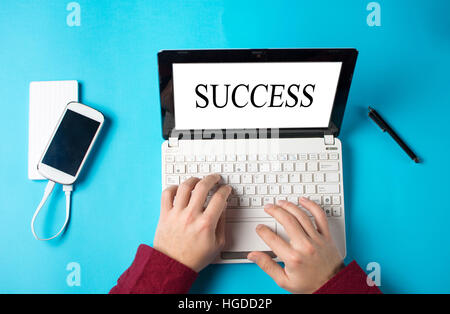 Mani maschio digitando una parola successo sul laptop bianco Foto Stock