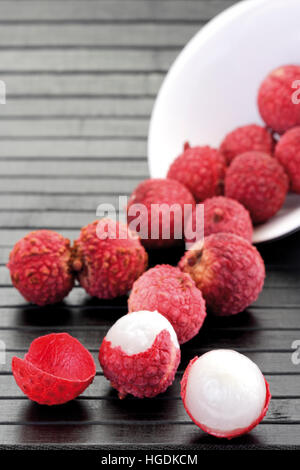 I litchi in una ciotola bianco su una tavola nera Foto Stock