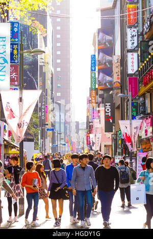 Ai giovani coreani camminando giù retroilluminato occupato a Myeongdong strada pedonale dello shopping con commercialismo di molti segni del negozio e affollati Foto Stock