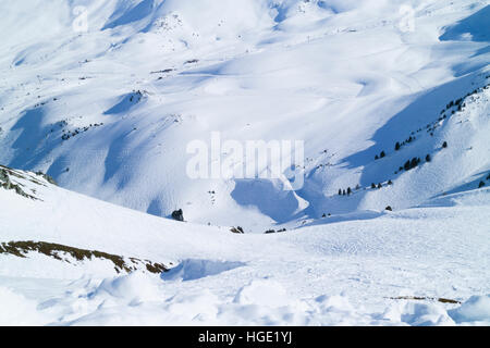 Montagna innevata valle attraversata da piste da sci su piste battute e i fuori pista Foto Stock