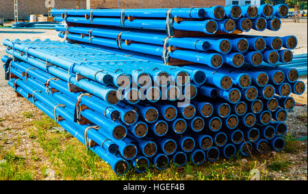 Pile di blu in PVC tubi di acqua in pila su open storage a un factory Foto Stock