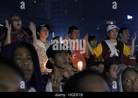 Manila, Filippine. 9 Gen, 2017. I devoti alza le mani al cielo in preghiera del Signore durante la messa di mezzanotte per celebrare la festa del Nazareno nero. Migliaia di devoti della icona religiosa il floccato Quirino Grandstand per prendere parte alla Messa e le altre attività nella celebrazione della festa del Nazareno nero. © Dennis Jerome Acosta/Pacific Press/Alamy Live News Foto Stock