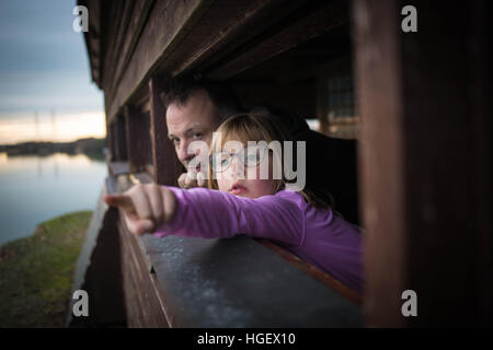 Un uomo e sua figlia look per uccelli in una pelle a Romney Marsh in Dungeness, Kent, Regno Unito Foto Stock