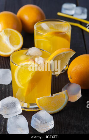 Due bicchieri con bevanda arancione sul buio tavolo in legno Foto Stock