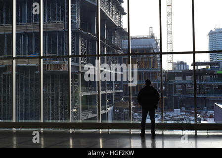 Un uomo si profila come egli sorge all'interno di Rogers Place arena in Edmonton, Alberta, Canada e si affaccia alla costruzione in corso Foto Stock