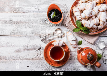 Rugelach con marmellata al riempimento sulla piastra con tè bianco su sfondo di legno, vista dall'alto con spazio di copia Foto Stock