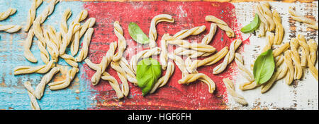 In casa la pasta cruda casarecce con la farina e il verde del basilico foglie Foto Stock