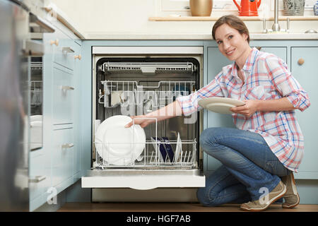 Donna caricamento di lavastoviglie in cucina Foto Stock