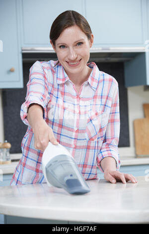 Donna di pulizia utilizzando cucina tenuto in mano aspirapolvere Foto Stock