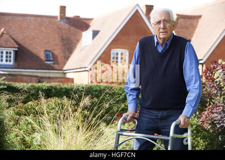 Senior l uomo nel giardino con telaio a piedi Foto Stock