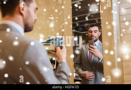 Uomo in tuta prendendo selfie specchio al negozio di abbigliamento Foto Stock