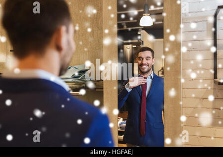 Uomo cerca sul tirante in corrispondenza dello specchio nel negozio di abbigliamento Foto Stock