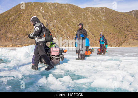 Lago Baikal, Russia - 24 Marzo 2016: gli uomini trascinato la Ice Sledge attraverso una fessura nel ghiaccio del Lago Baikal nel Marzo 24, 2016 Foto Stock