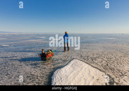 Ragazza con una mazza e trekking pole è sul ghiaccio del lago Baikal. Foto Stock