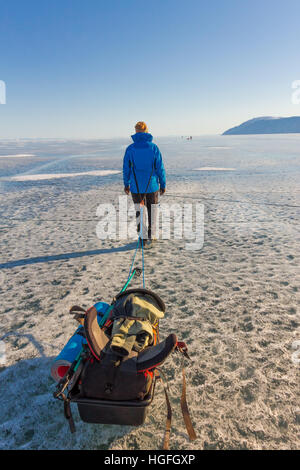 Ragazza con una mazza e trekking pole è sul ghiaccio del lago Baikal. Foto Stock