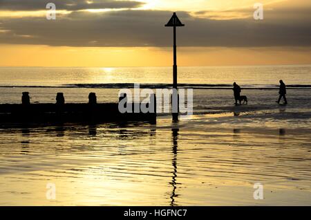 La gente che camminava un cane su Borth spiaggia al tramonto Ceredigion nel Galles Cymru REGNO UNITO GB Foto Stock