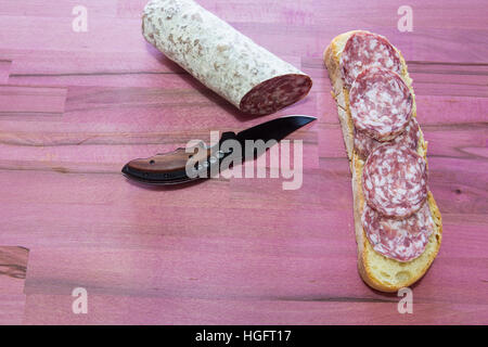 Il coltello taglia il salame su un asse di legno Foto stock - Alamy