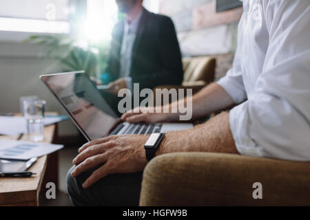 Imprenditore lavora su computer portatile durante la riunione aziendale. La gente di affari avente una riunione in ufficio. Foto Stock