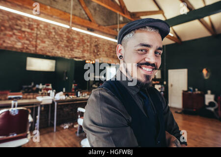 Close up di successo della giovane uomo con cappuccio in salone. Bello il parrucchiere sorridente al barbiere. Foto Stock