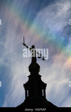 Signora Giustizia in cima alla Old Bailey a Londra, stagliano contro una vibrante blu cielo con un debole rainbow. Foto Stock