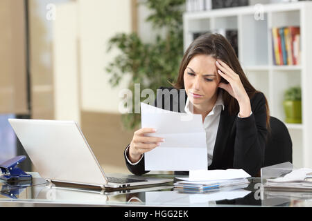 Preoccupato imprenditrice la lettura di una seduta di notifica in un desktop in ufficio Foto Stock