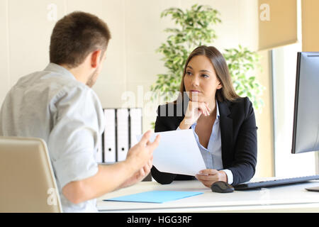 Uomo in cerca di occupazione in un pessimo lavoro intervista con l'intervistatore guardando diffidente Foto Stock