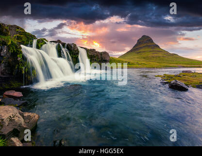 Estate tramonto sulla famosa cascata Kirkjufellsfoss Kirkjufell e montagna. Serata drammatica scena sulla penisola Snaefellsnes Foto Stock