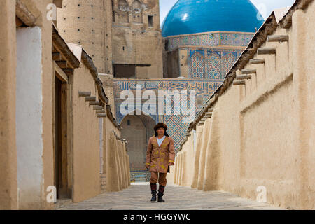 Il kazako uomo in costumi nazionali con le cupole blu di Khoja Ahmed Yasawi Mausoleo in background, Turkestan, Kazakistan Foto Stock