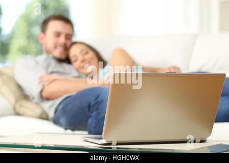 Paio di guardare la tv in un computer portatile sdraiato su un lettino a casa Foto Stock