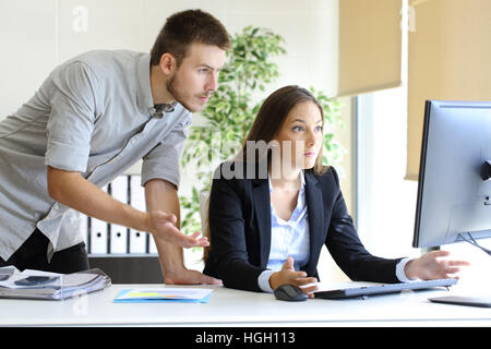 Turbare gli imprenditori cercano di lavorare in linea con un computer desktop guardando il monitor in ufficio Foto Stock