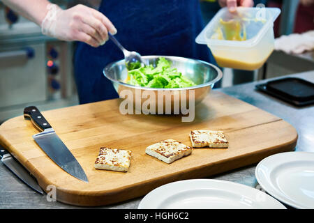 La preparazione di piatti a base di formaggio fritto e insalata verde in ristorante Foto Stock