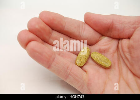 Due compresse multivitaminico nel palmo della mano Foto Stock