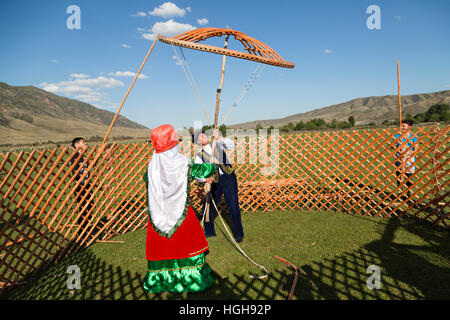 Popolo nomade in costumi nazionali la costruzione di una yurta e trattenere la corona della cupola di yurta noto come Shangyrak Shanyrak o. Foto Stock