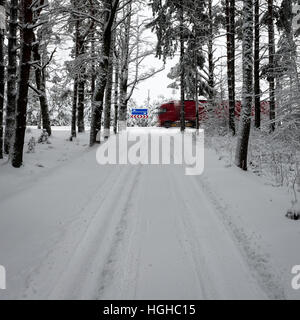 Auto tracce di pneumatici sulla strada invernale nella neve profonda nella foresta di solitario con cartelli stradali Foto Stock