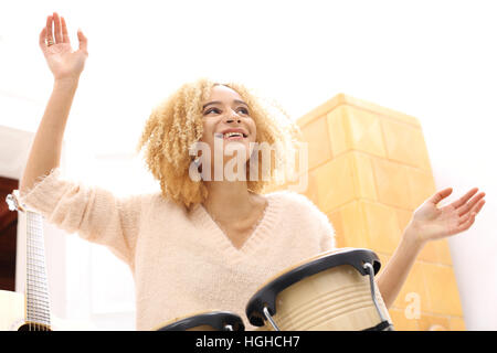 La musica. Crea la tua musica. Battendo il ritmo dei tamburi. Bongo, percussione. Ragazza che gioca i tamburi di bongo, tamburi piccoli. Foto Stock