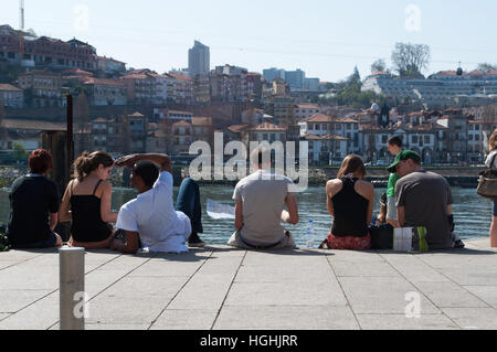 Porto, Portogallo, Europa: persone agghiacciante di fronte lo skyline di Vila Nova de Gaia si vede dalle sponde del fiume Douro nella città vecchia Foto Stock
