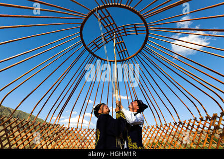 Il kazako uomini costruire una yurta e tenere la corona della cupola nel villaggio di soggiornare, Kazakistan Foto Stock