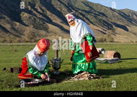 Il kazako donne in costumi nazionali cucinare all'aperto, nel villaggio di soggiornare, Kazakistan Foto Stock