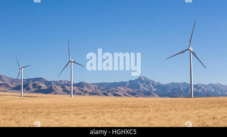 Tre mulini a vento sono parte di una grande fattoria eolica nel sud dello Utah vicino alla città di Milford. In fondo è il celeberrimo picco di granito del minerale Foto Stock