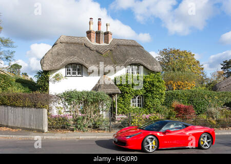 Ferrari auto sportive passando cottage con il tetto di paglia al Swan verde, Lyndhurst, Hampshire, Inghilterra, Regno Unito Foto Stock