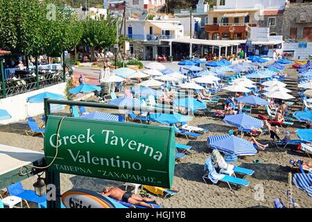 Taverna Greca Valentino segno sul bordo della spiaggia con i turisti rilassante alla parte posteriore, Bali, Creta, Grecia, l'Europa. Foto Stock