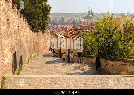 I turisti salire le scale vicino al castello di Hradcany, Malá Strana, con vista sulla chiesa di San Nicola e la città di Praga di seguito. Foto Stock