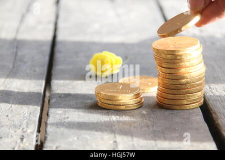 Pila di monete con la mano sul tavolo in legno Foto Stock