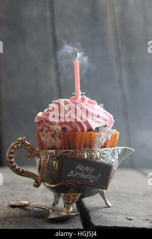 Tortina di compleanno con una candela e del fumo sulla tabella rurale Foto Stock