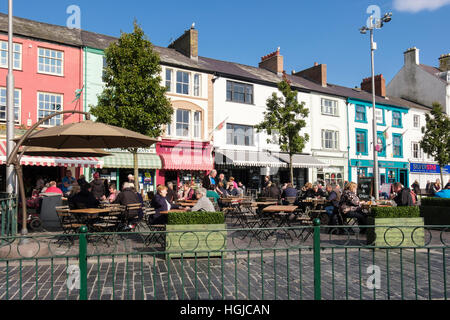 Persone per mangiare fuori nel sole in piazza street cafe. Caernarfon, Gwynedd, il Galles del Nord, Regno Unito, Gran Bretagna Foto Stock