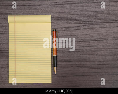Scrivania di legno scuro, giallo Pad, la penna sulla scrivania Foto Stock